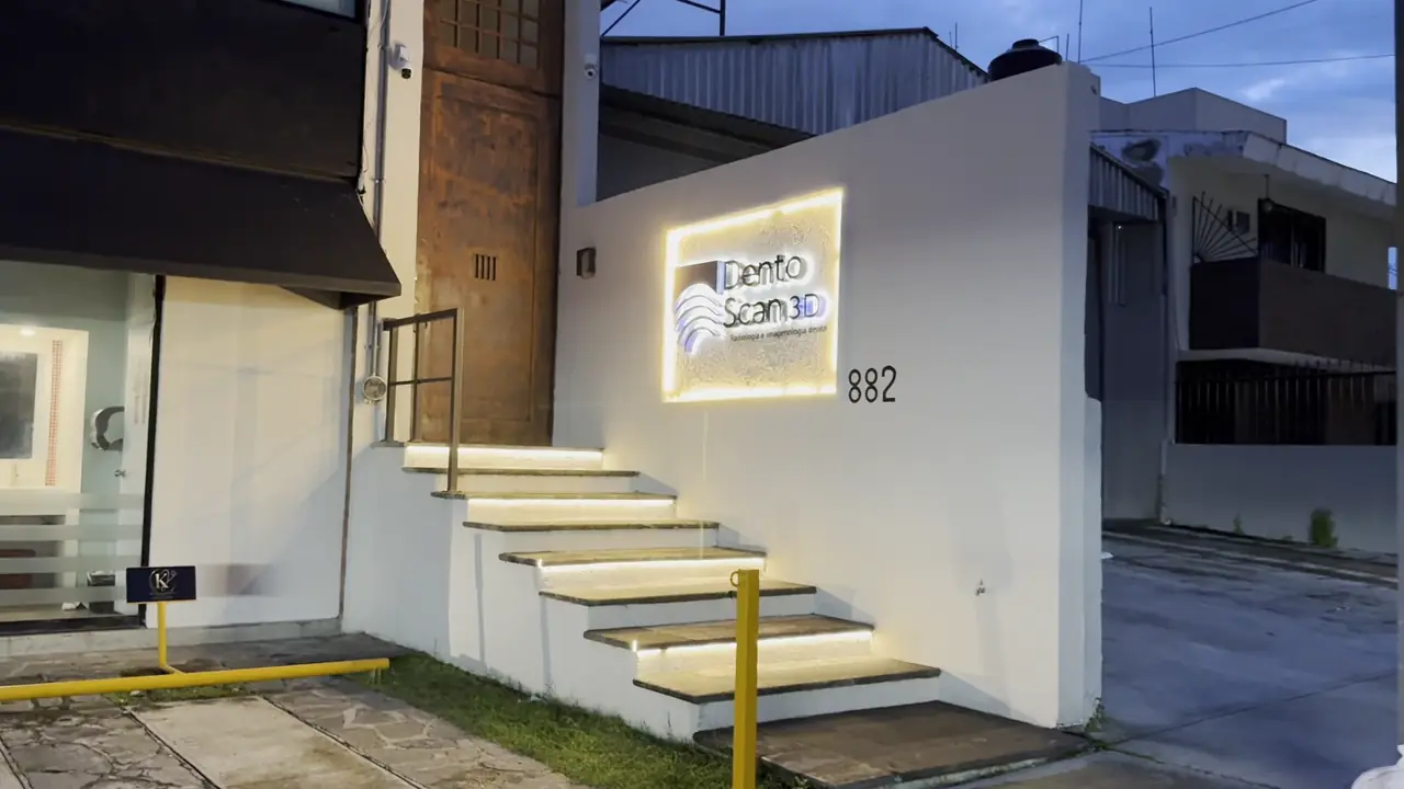 Entrada de Dento Scan 3D al anochecer, con el letrero iluminado y la escalera